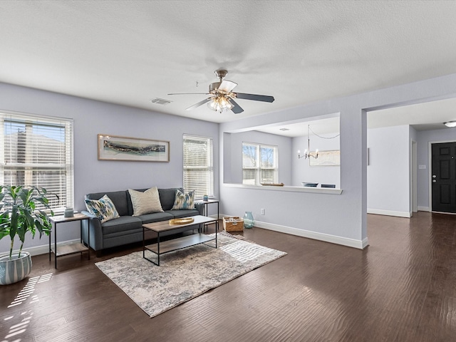 living room with plenty of natural light, dark hardwood / wood-style flooring, ceiling fan with notable chandelier, and a textured ceiling