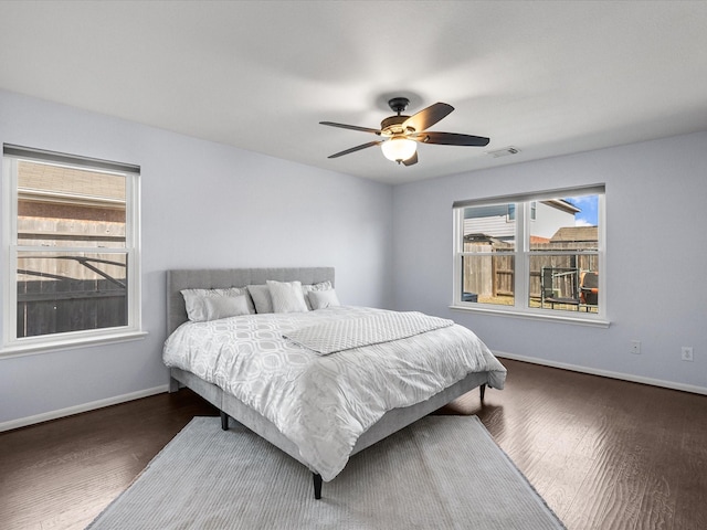 bedroom with multiple windows, dark hardwood / wood-style floors, and ceiling fan