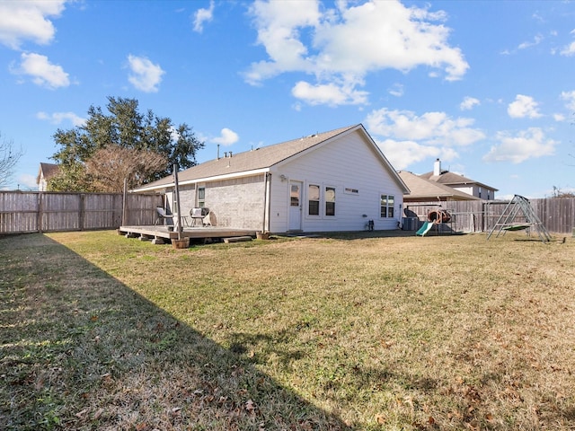 back of house featuring a playground, a yard, and a deck