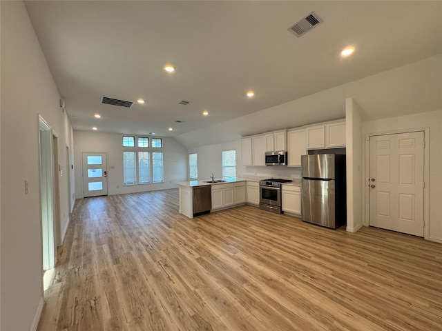 kitchen with white cabinets, lofted ceiling, stainless steel appliances, sink, and kitchen peninsula