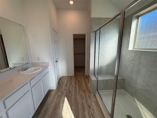 bathroom featuring hardwood / wood-style floors, a shower with door, and vanity