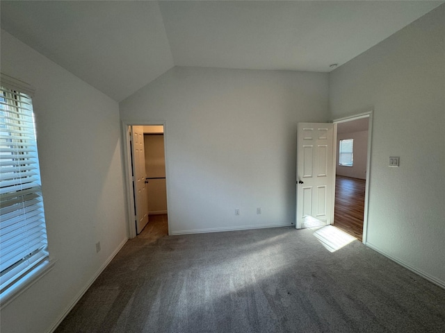 unfurnished bedroom with vaulted ceiling, a walk in closet, and carpet flooring