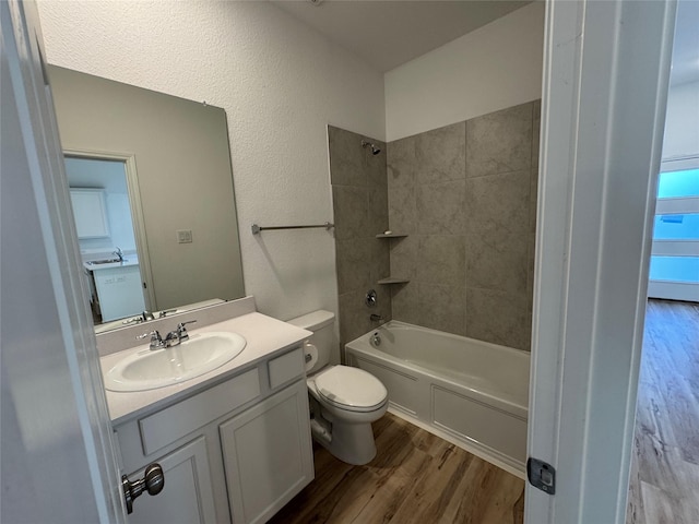 full bathroom featuring hardwood / wood-style floors, toilet, tiled shower / bath, and vanity