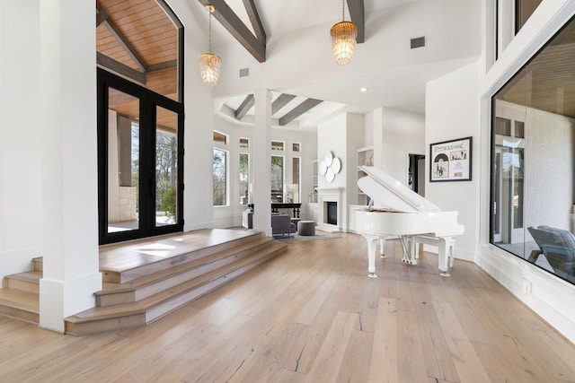 entrance foyer featuring french doors, beam ceiling, light hardwood / wood-style flooring, and a high ceiling