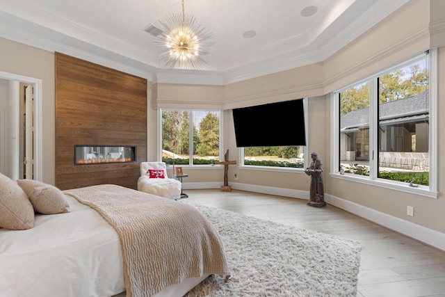 bedroom with a chandelier, crown molding, a raised ceiling, and light hardwood / wood-style floors