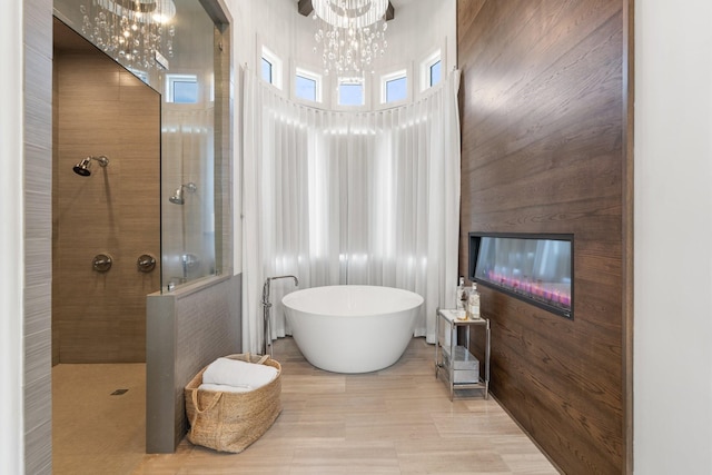 bathroom featuring tile patterned floors, wood walls, a chandelier, separate shower and tub, and a towering ceiling