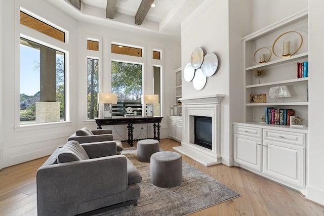 living room featuring built in features, beam ceiling, light hardwood / wood-style flooring, and a wealth of natural light