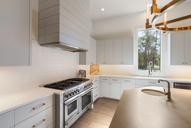 kitchen featuring sink, white cabinetry, custom range hood, range with two ovens, and backsplash