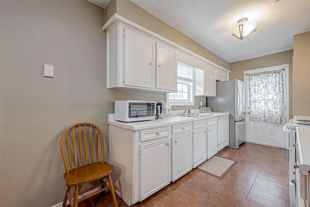 kitchen featuring light tile patterned floors, sink, white appliances, and white cabinets