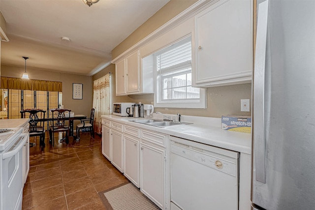 kitchen with white appliances, dark tile patterned floors, decorative light fixtures, white cabinetry, and sink