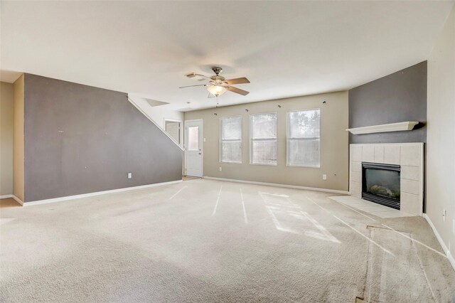 unfurnished living room featuring ceiling fan, light colored carpet, and a tiled fireplace