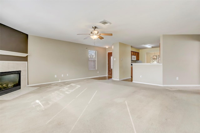 unfurnished living room featuring ceiling fan, light colored carpet, and a tiled fireplace