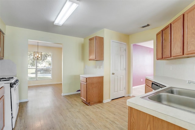 kitchen featuring a notable chandelier, white gas stove, light hardwood / wood-style floors, hanging light fixtures, and sink