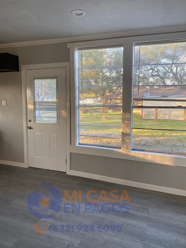 interior space featuring dark wood-type flooring, ornamental molding, and a textured ceiling