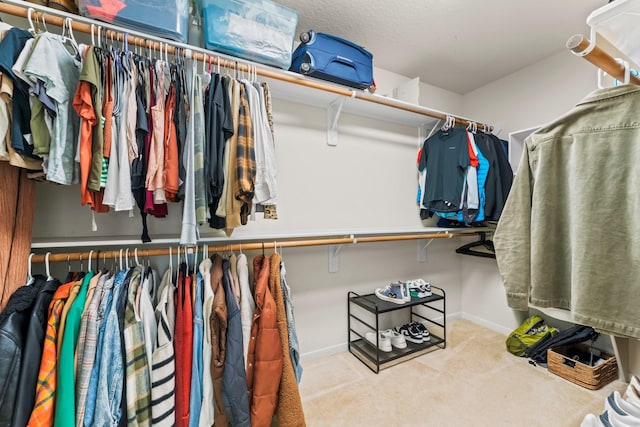 walk in closet with light carpet