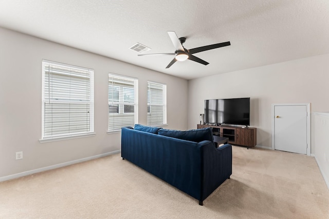 living room with ceiling fan, light colored carpet, and a textured ceiling