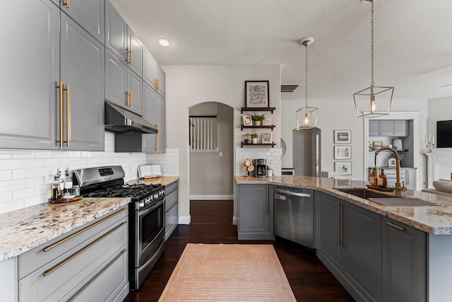 kitchen featuring stainless steel appliances, light stone countertops, gray cabinetry, and decorative light fixtures