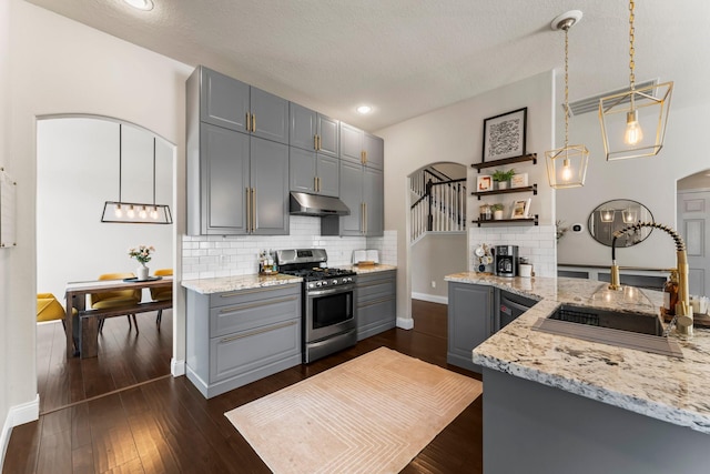 kitchen featuring sink, gas stove, gray cabinets, pendant lighting, and light stone countertops