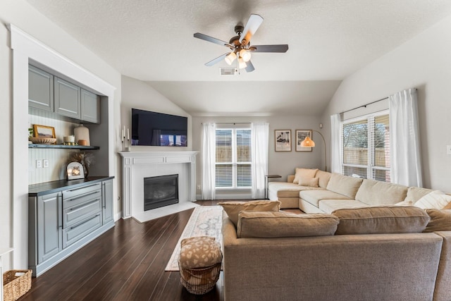 living room featuring ceiling fan, lofted ceiling, dark hardwood / wood-style floors, and a textured ceiling