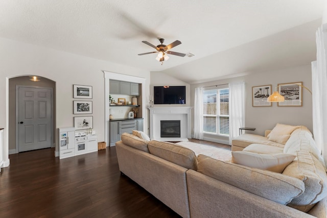 living room with lofted ceiling, a textured ceiling, dark wood-type flooring, and ceiling fan