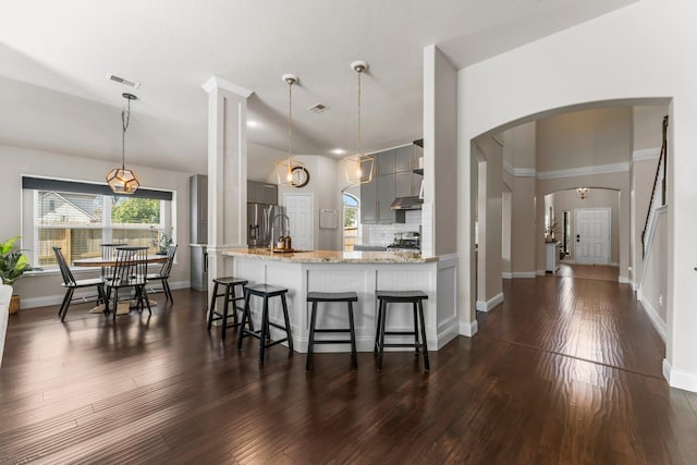 kitchen featuring gray cabinets, pendant lighting, dark hardwood / wood-style flooring, kitchen peninsula, and light stone countertops