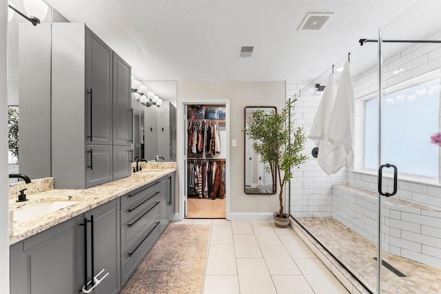 bathroom with tile patterned flooring, vanity, an enclosed shower, and a textured ceiling