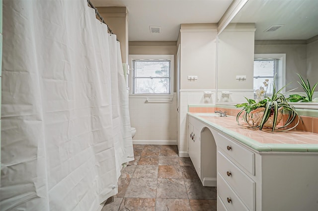 bathroom with plenty of natural light, tile walls, toilet, and vanity