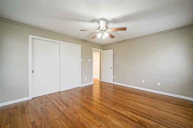 unfurnished bedroom featuring crown molding, a textured ceiling, wood-type flooring, a closet, and ceiling fan