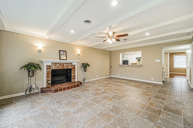 unfurnished living room with ceiling fan, a textured ceiling, beam ceiling, and a fireplace