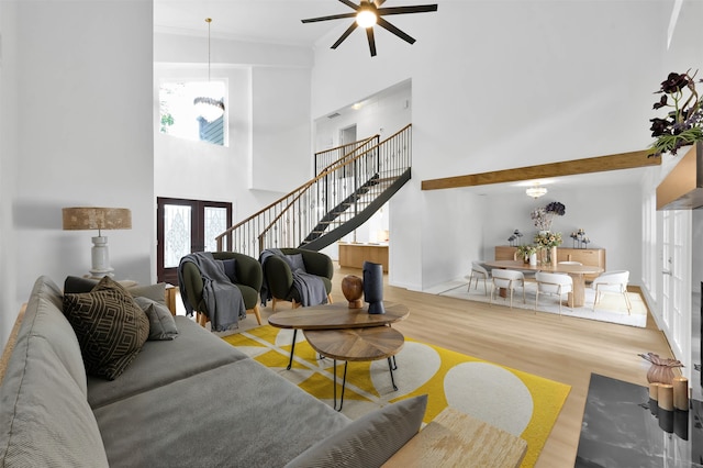 living room with a notable chandelier, a towering ceiling, french doors, and light hardwood / wood-style floors