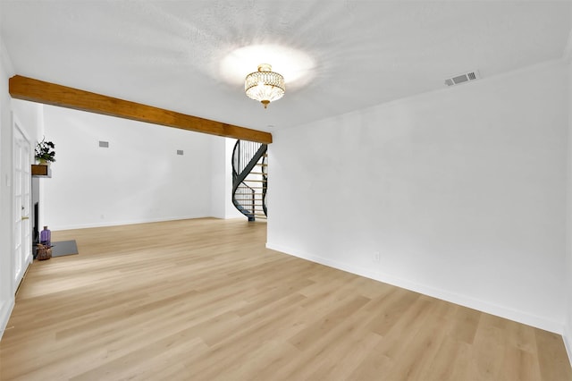 unfurnished living room featuring light hardwood / wood-style floors, beam ceiling, and a notable chandelier