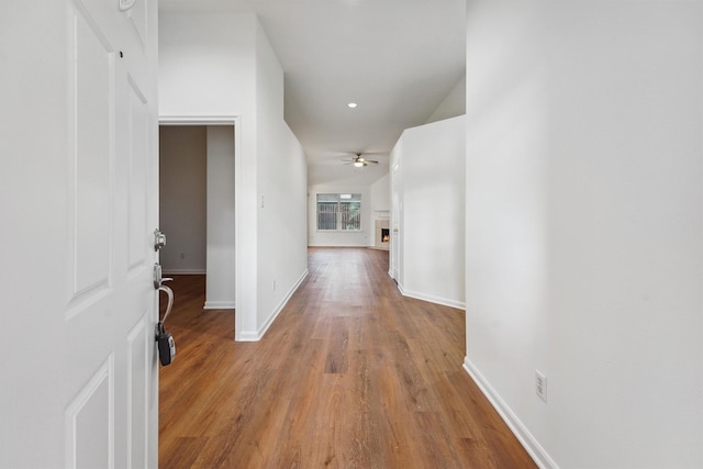 corridor with vaulted ceiling and hardwood / wood-style floors