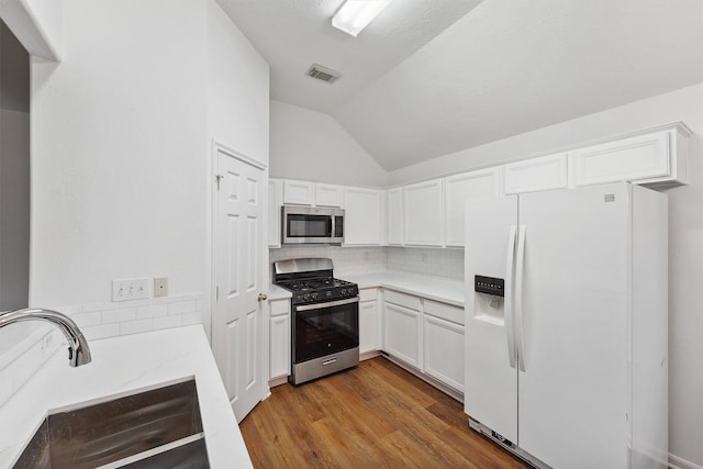 kitchen featuring tasteful backsplash, range with gas stovetop, white refrigerator with ice dispenser, white cabinets, and sink