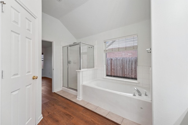 bathroom with wood-type flooring, independent shower and bath, and vaulted ceiling