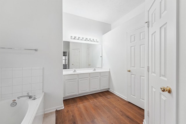 bathroom featuring hardwood / wood-style flooring, a textured ceiling, vanity, and a bath