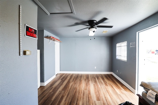 unfurnished room featuring hardwood / wood-style flooring, ceiling fan, and a textured ceiling