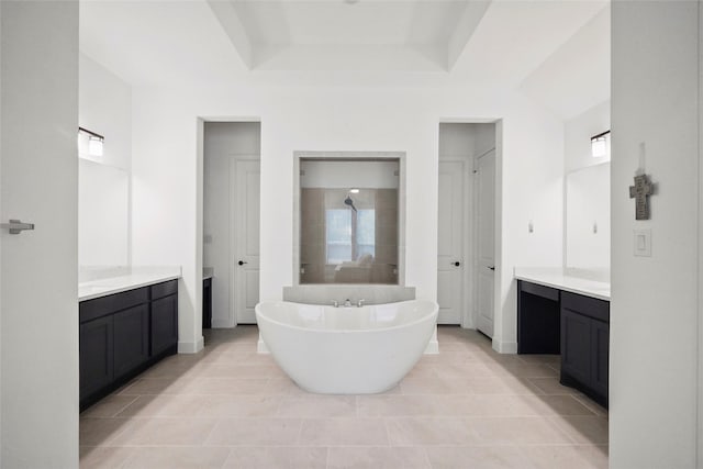 bathroom with tile patterned flooring, a raised ceiling, vanity, and a tub to relax in