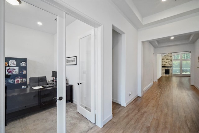 hall with a raised ceiling and light hardwood / wood-style floors