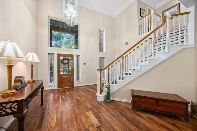 entrance foyer featuring hardwood / wood-style flooring, ornamental molding, a towering ceiling, and a chandelier