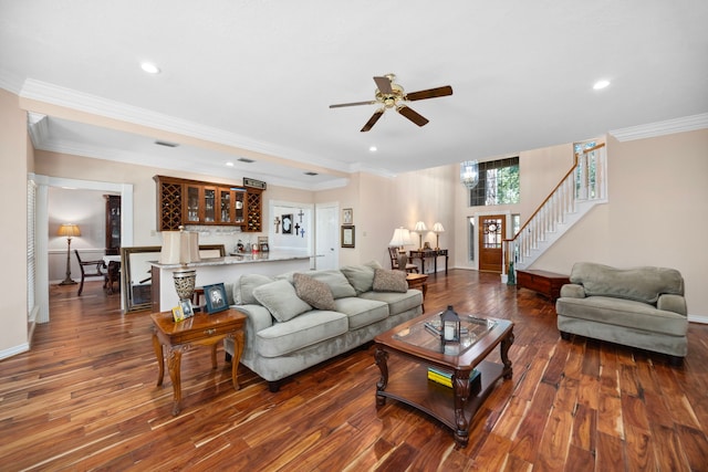 living room featuring bar, dark wood-type flooring, ornamental molding, and ceiling fan