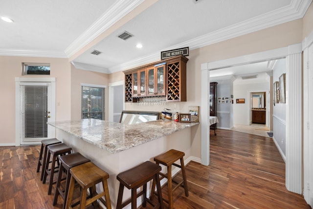 kitchen featuring crown molding, dark hardwood / wood-style flooring, kitchen peninsula, and a breakfast bar area