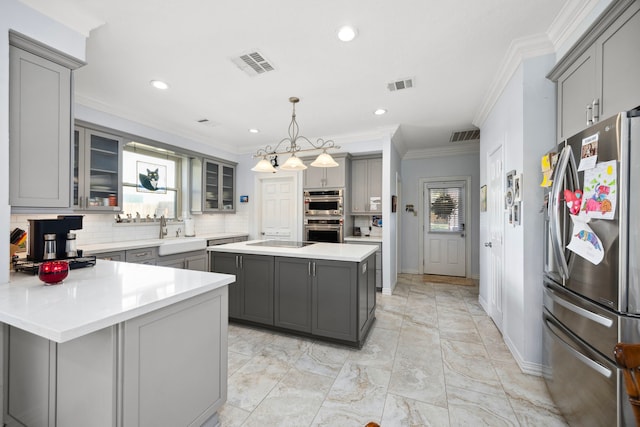 kitchen with pendant lighting, sink, appliances with stainless steel finishes, gray cabinetry, and a center island