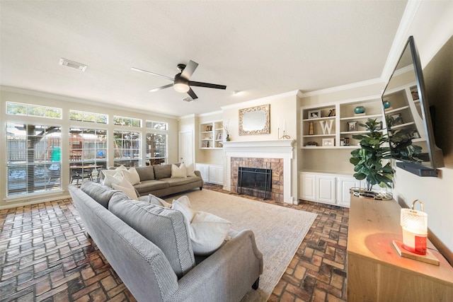 living room featuring crown molding, ceiling fan, and a fireplace