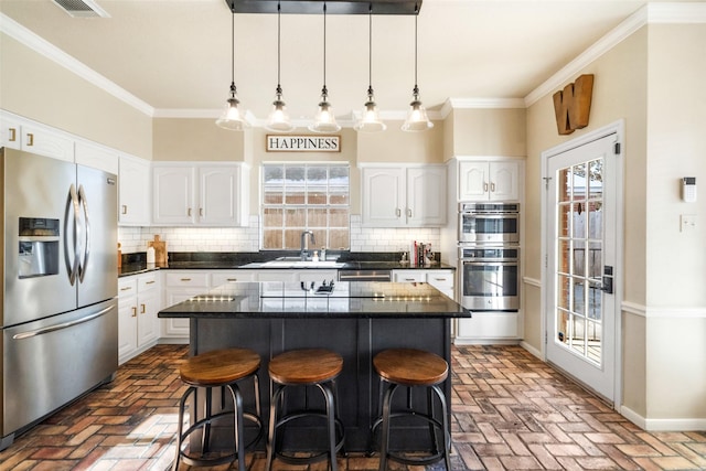 kitchen featuring white cabinetry, backsplash, hanging light fixtures, stainless steel appliances, and a center island