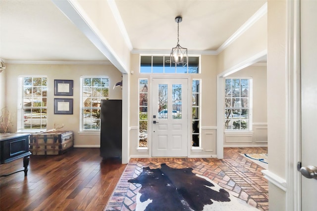 foyer entrance featuring crown molding, dark hardwood / wood-style floors, and an inviting chandelier