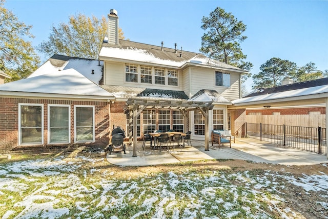 snow covered rear of property featuring a pergola and a patio