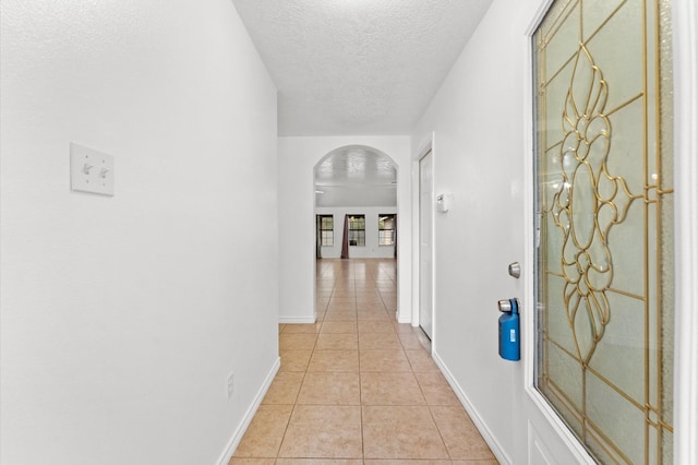 corridor featuring light tile patterned floors and a textured ceiling