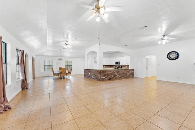 unfurnished living room featuring ceiling fan, vaulted ceiling, and light tile patterned floors