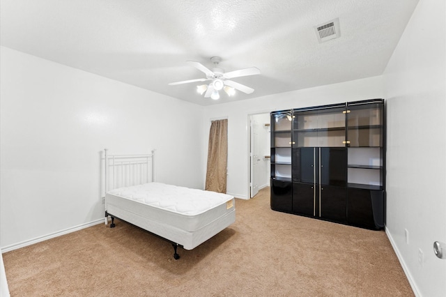 carpeted bedroom featuring ceiling fan and a textured ceiling