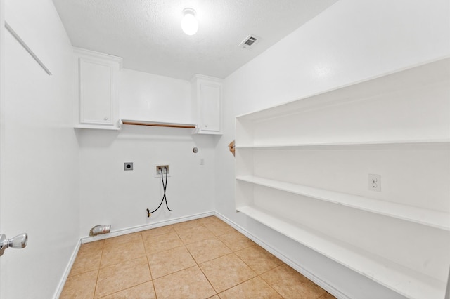 clothes washing area featuring gas dryer hookup, electric dryer hookup, hookup for a washing machine, cabinets, and a textured ceiling